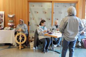 Lonnie Archibald/for Peninsula Daily News Forks Timber Museum manager Linda Offett (back to camera) looks on while from left Jennifer Pelikan spins, Debbie Anderson knits and Janet Gilmore works on a basket Saturday at the Arts and Crafts Show at the Rainforest Arts Center in Forks. The artistic work is part of Hickory Shirt Heritage Days festival which continues today.