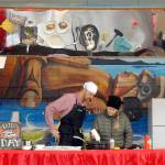 Celebrity cheff Nathan Shields of Saipancakes in Port Angeles, left, gets assistance from audience member Haley Snider of Port Angeles with making decorated pancakes during a cooking demonstration in the pavilion at The Gateway transit center, a venue of the Dungeness Crab and Seafood festival in downtown Port Angeles. (Keith Thorpe/Peninsula Daily News)