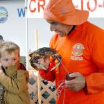 Three-year-old Hayden Fuller of Seabeck is wary as Robert Rohner of Sequim, a member of the North Olympic Peninsula Chapter of Puget Sound Anglers, gives the youngster a close up view of the crab he just caught during Saturdays crab derby at Port Angeles City Pier, a featured event of the Dungeness Crab and Seafood Festival. (Keith Thorpe/Peninsula Daily News)