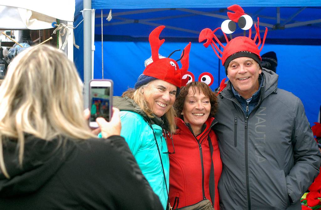 Denise Stephens of Surry, B.C., left, takes a photograph of crab hats worn by her friends, from left, of Sharon and Dave Cherry of Surry, and Cathie Hagenson of Comox, B.C., on Saturday at the Dungeness Crab and Seafood Festival in Port Angeles. (Keith Thorpe/Peninsula Daily News)