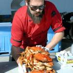 Crab cook Quintan Chastain of Port Angeles places a stack of crabs on a table for purchase near the crab derby tanks at Port Angeles City Pier on Friday. (Keith Thorpe/Peninsula Daily News)