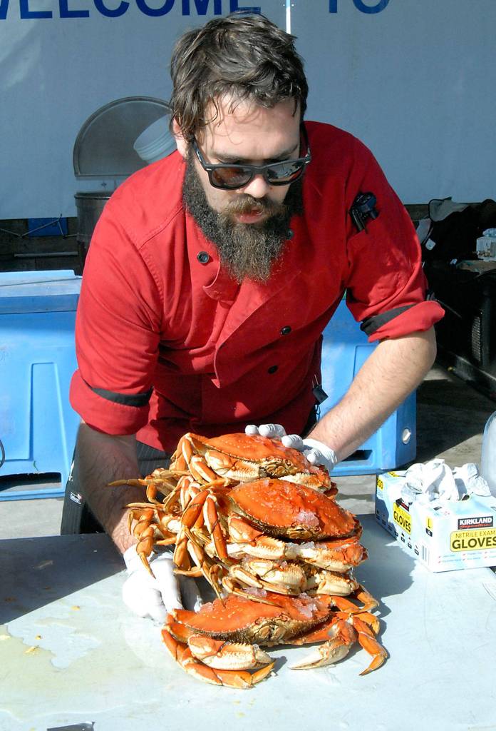 Crab cook Quintan Chastain of Port Angeles places a stack of crabs on a table for purchase near the crab derby tanks at Port Angeles City Pier on Friday. (Keith Thorpe/Peninsula Daily News)