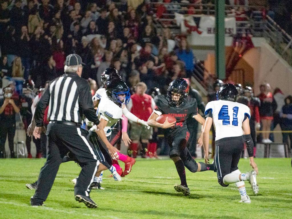 Steve Mullensky/for Peninsula Daily News Redhawk Dylan Tracer finds a hole in the Bellevue Christian defense and runs for a first down during a game on Friday at Memorial Field.