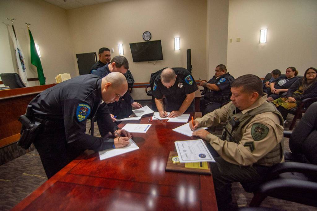 Lower Elwha Police Department officers sign paperwork after being sworn in. (Jesse Major/Peninsula Daily News)