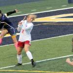Spartan Candida-Rose Sandoval (left) kicks past Hoquiams Sadie Carlyle (2) during a rain storm at Spartan Stadium where the Grizzlies defeated Forks 2-0 on a wet and windy Spartan Stadium turf. Forks wore pink socks and used a pink and white soccer ball during this cancer awareness night. (Lonnie Archibald/for Peninsula Daily News)