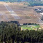 The 6,347-foot long main runway at William R. Fairchild International Airport in Port Angeles, known officially as 8/26, is shown in this July 2011 file photo. The heavily-forested Lincoln Park with its athletic fields is shown at bottom. (Keith Thorpe/Peninsula Daily News)