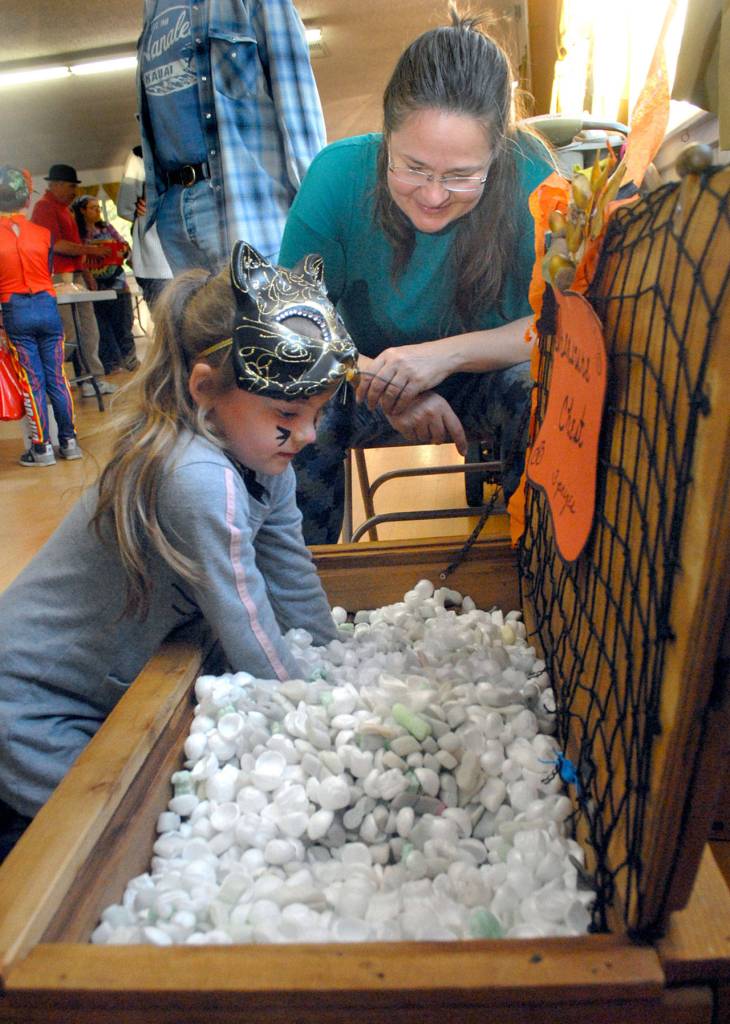 Lexie Lind, 7, of Sequim reaches to the bottom of a treasure chest for candy treats as Sequim Prairie Grange member Becky Horst looks on during Saturdays Pumpkin Party. (Keith Thorpe/Peninsula Daily News)