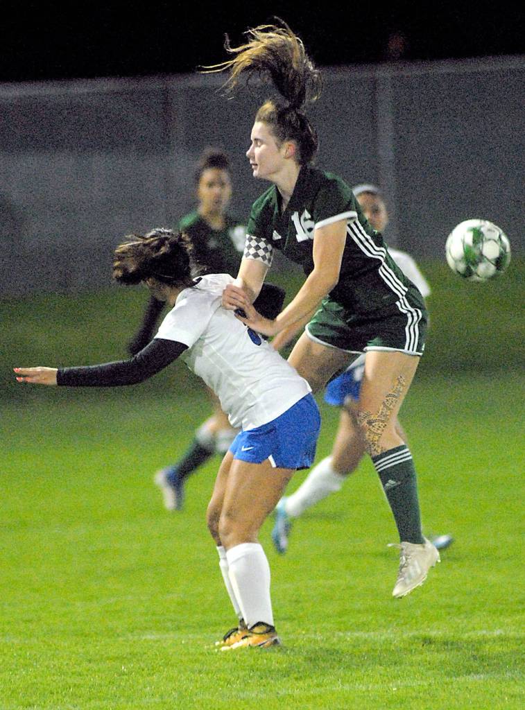 Keith Thorpe/Peninsula Daily News Port Angeles Delaney Wenzl goes up and over Olympics Alexis Valenzuela on Tuesday night at Port Angeles Civic Field.