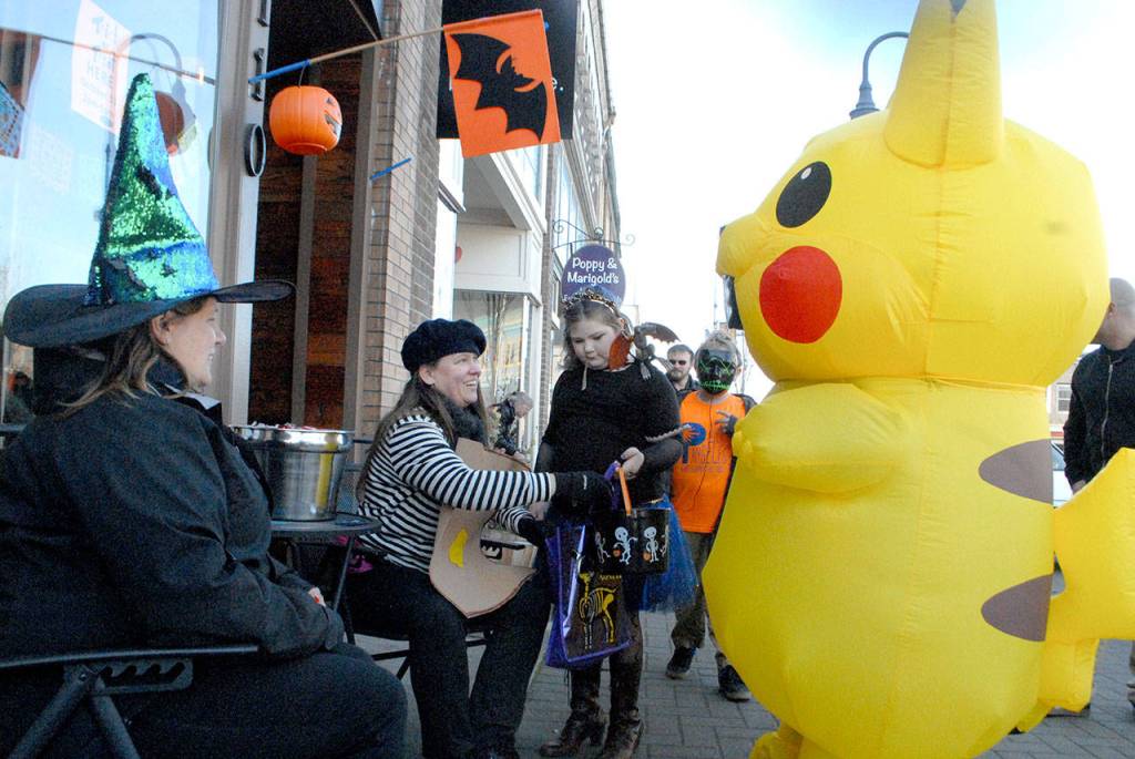 Melissa Williams, left, and Carrie Sanford give treats to 8-year-old Norah Haire, center, and Lilly Spoon, 12, in front of barbecue in downtown Port Angeles on Thursday. (Keith Thorpe/Peninsula Daily News)