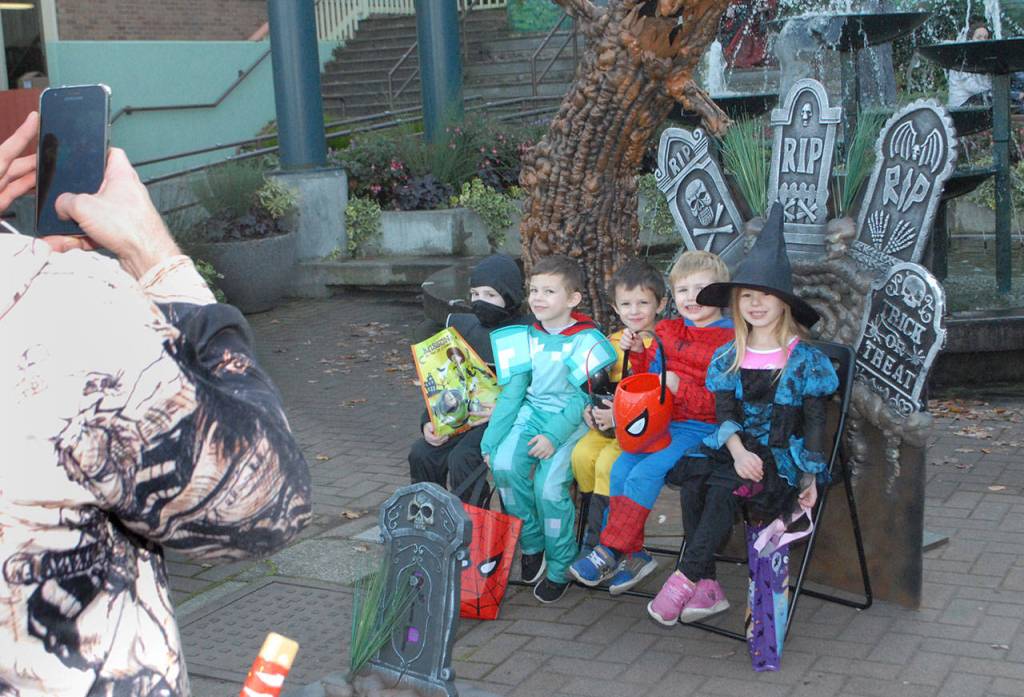 Brett Stigall of Port Angeles, left, takes a photo of youngsters, from left, Dawkin Stigall, 7, Cael Stigall, 6, Tydus Stigall, 4, Gary Proutt, 3, and Gloria Proutt, 5, at the plaza at the Conrad Dyar Memorial Fountain in downtown Port Angeles on Halloween. (Keith Thorpe/Peninsula Daily News)