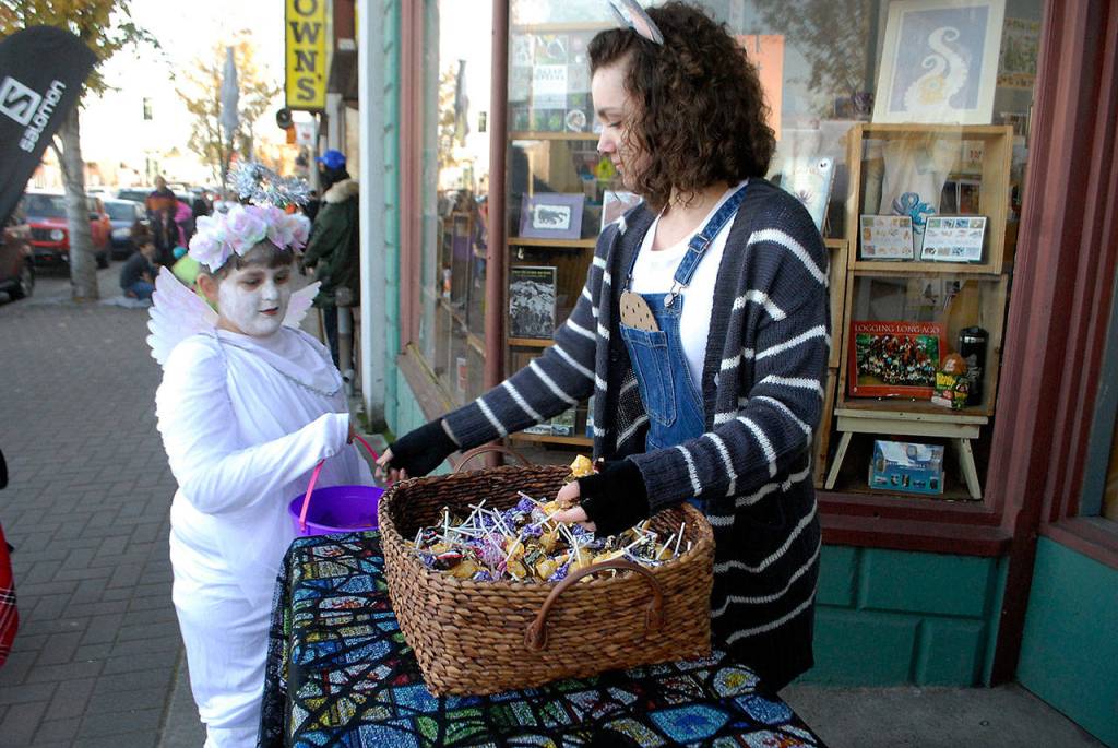 Karissa Reese, 9, of Port Angeles, trick or treats as an angel to receive a handout from Sarah Kauffman, an employee of Odyssey Bookshop, during Halloween festivities in downtown Port Angeles. (Keith Thorpe/Peninsula Daily News)