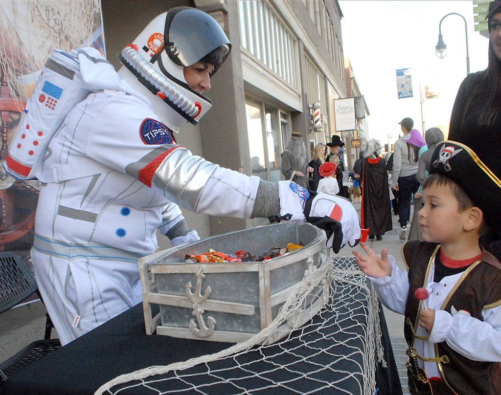 Shelly Treider, an employee of Platypus Marine Inc., passes out a treat to four-year-old Kameron Flores of Port Angeles. (Keith Thorpe/Peninsula Daily News)