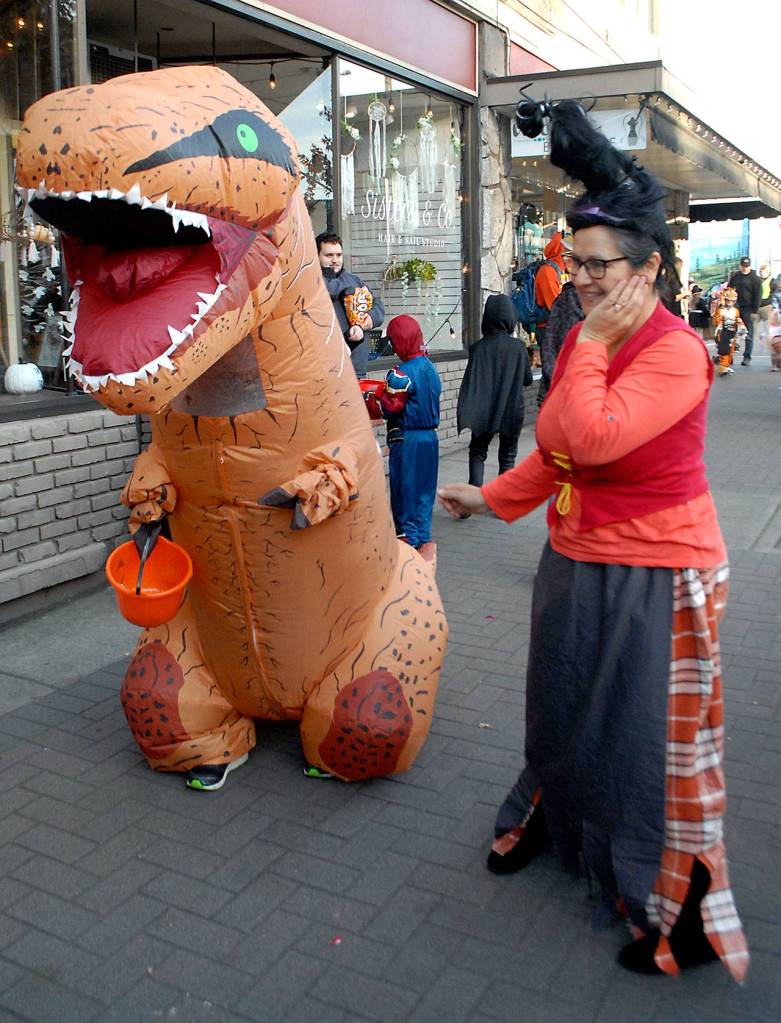 Andy Walters, 8, waddles down Front Street in his T-rex costume as his mother, Imelda Walters of Port Angeles, guides him through crowds of trick-or-treaters on Halloween in Port Angeles. (Keith Thorpe/Peninsula Daily News)