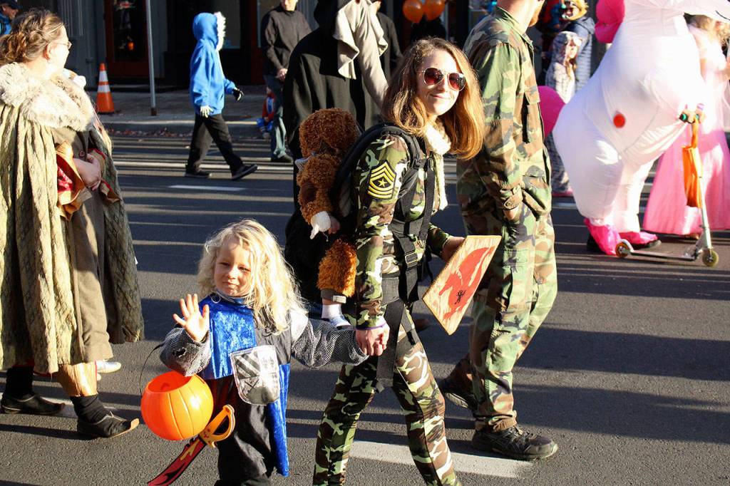 Remington Hampton waves to the crowd as he walks down Water Street with his family in Port Townsend during the Halloween Parade. (Zach Jablonski/Peninsula Daily News)