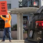 Anti-tax activist Tim Eyman holds a sign supporting Initiative 976, which would cut most car registration tabs to $30 in Washington state, Tuesday on election day in Bellevue. (Ted S. Warren/The Associated Press)