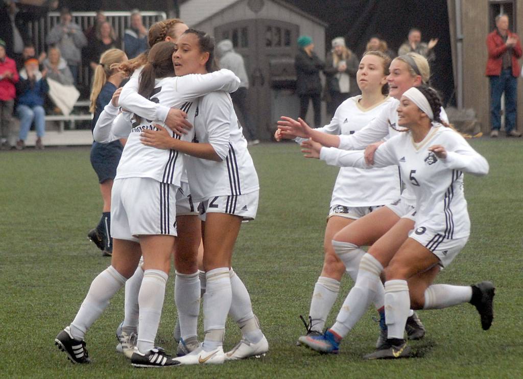 Keith Thorpe/Peninsula Daily News Peninsula players rush to congratulate teammate Sam Oliveira, left, after she scored the first goal against Bellevue in Saturdays quarter-final match in Port Angeles.