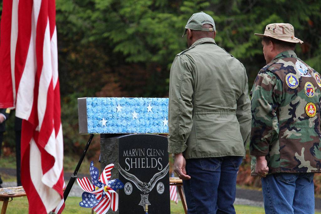 Retired Senior Chief Todd Bolden, left, and retired Chief Petty Officer Eric Corley stand at attention after placing flowers on Petty Officer Marvin G. Shields headstone doing the honor ceremony held Monday morning at the Gardiner Cemetery. (Zach Jablonski/Peninsula Daily News)