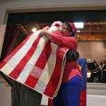 John Carter, who served in the U.S. Navy, receives a hug from a volunteer after he was presented one of the Jefferson County Quilts of Valor on Monday during the Port Townsend American Legion Post 26 Veterans Day ceremony. (Brian McLean/Peninsula Daily News)