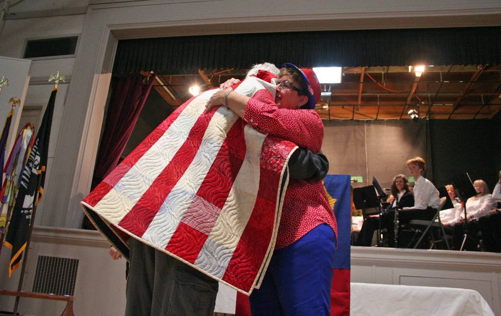 John Carter, who served in the U.S. Navy, receives a hug from a volunteer after he was presented one of the Jefferson County Quilts of Valor on Monday during the Port Townsend American Legion Post 26 Veterans Day ceremony. (Brian McLean/Peninsula Daily News)