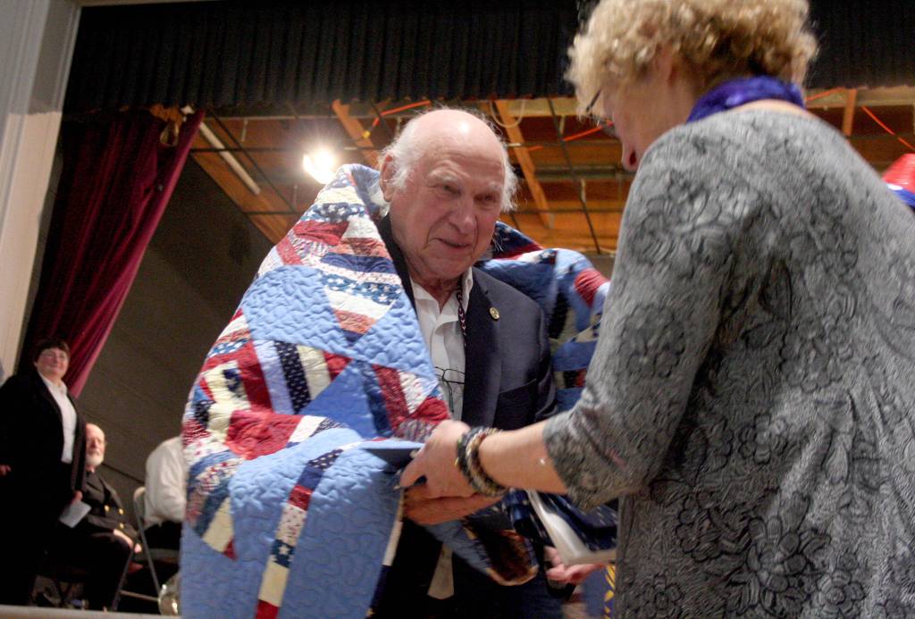 Chuck Henry, who served in the U.S. Air Force, is enveloped in one of the Jefferson County Quilts of Valor on Monday during the American Legion Post 26 Veterans Day ceremony in Port Townsend. (Brian McLean/Peninsula Daily News)