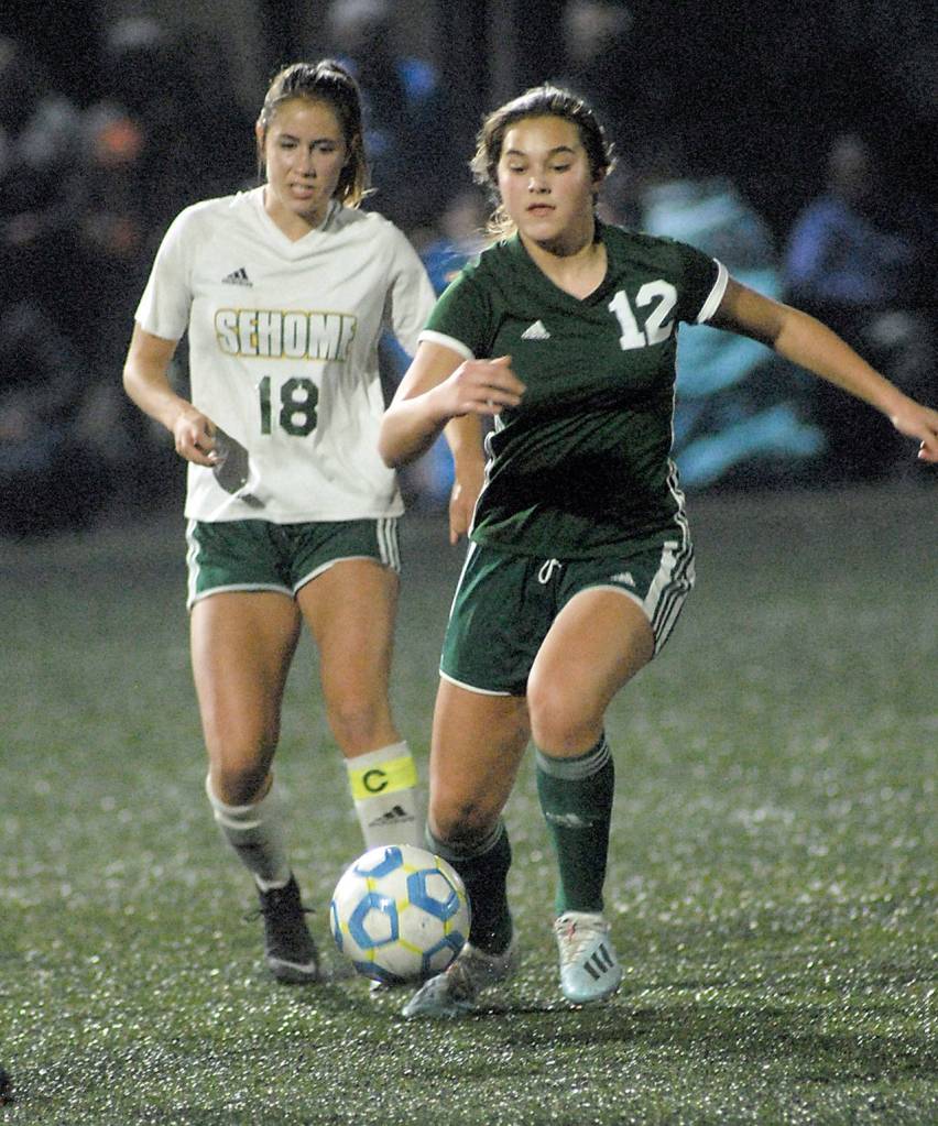 Port Angeles Eve Burke, right, drives down the pitch with Sehomnes Zola Carbone on her heels at Wally Sigmar Field on Tuesday night. (Keith Thorpe/Peninsula Daily News)