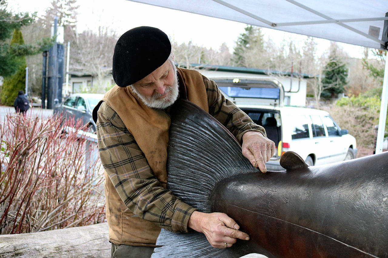 Artist Tom Jay shows the area that the vandal cut, demonstrating with his hands how long the cut stretched. (Nicole Jennings)