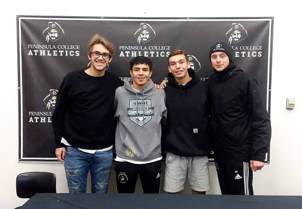 Peninsula College soccer players, from left, Evan Scholes, Edgar Tavares, Mason Haubrich and head coach Jake Hughes gathered on campus Monday after winning the NWAC championship Sunday. (Pierre LaBossiere/Peninsula Daily News)