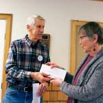 President of Olympic Pet Pals Pam Kolacy receives a check for $220 from Bob Bindscaldler of the Quilcene-Brinnon Garden Club on Thursday afternoon at the Quilcene Community Center to help provide free spay and neuter services. (Zach Jablonski/Peninsula Daily News)