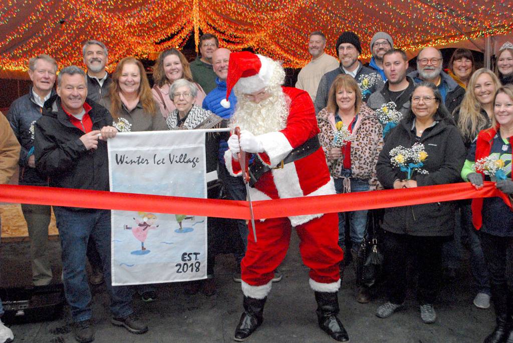 Santa Claus, portrayed by Port Angeles High School Key Club member Cole Walsh, cuts the ribbon to officially open the skating rink at the Port Angeles Ice Village. (Keith Thorpe/Peninsula Daily News)