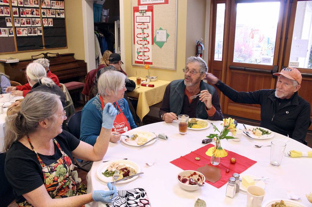 Volunteers Linda Nolan, left, and Norma VanValkenburq share a meal with community members Bill Dentzel and Jim Kretz during the St. Pauls Episcopal Church Thanksgiving meal Wednesday afternoon. (Zach Jablonski/Peninsula Daily News)