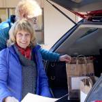 Volunteers A.K. Smiley and her husband Mike Smiley load the back of their vehicle with Thanksgiving meals, as they help deliver more than 90 meals to housebound community members. (Zach Jablonski/Peninsula Daily News)