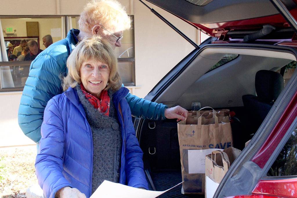 Volunteers A.K. Smiley and her husband Mike Smiley load the back of their vehicle with Thanksgiving meals, as they help deliver more than 90 meals to housebound community members. (Zach Jablonski/Peninsula Daily News)