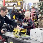 Don Droz of Swains hastily checks out Marie Jacobs of PA with her toy purchases as the shoppers streamed into the store at 7 a.m. Friday. Several dozen customers braved the dark and the cold to find that Black Friday special deal. (Dave Logan/For Peninsula Daily News)