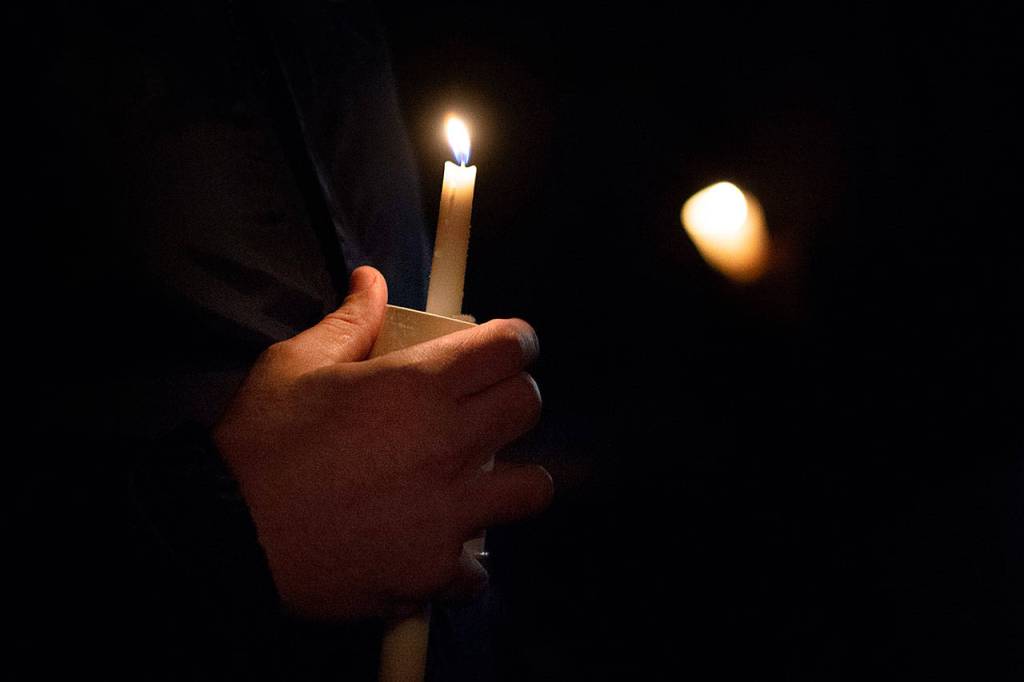 Spartans football coach Emil West holds a candle as he speaks about Tristen Pisani during the vigil for Pisani on Thursday. (Jesse Major/Peninsula Daily News)