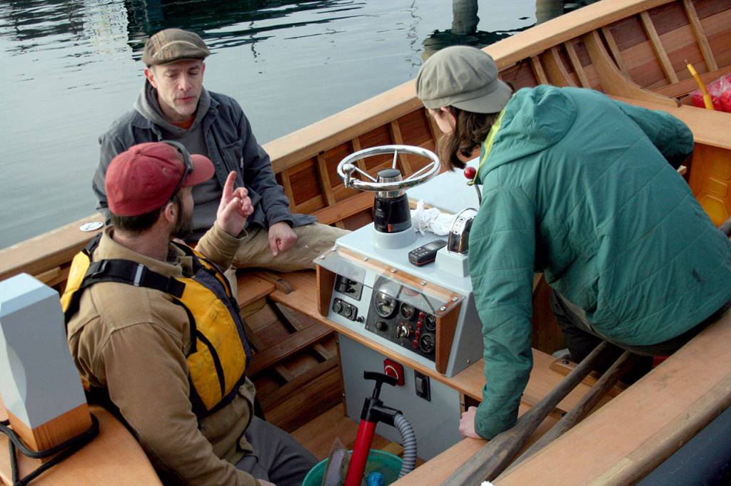 From left, Jody Boyle, Bill Billingsley and Demian Detweiler work on the systems of the Orca, an 18-foot Gartside workboat launched Monday after two years of work at the Northwest School of Wooden Boatbuilding. (Brian McLean/Peninsula Daily News)