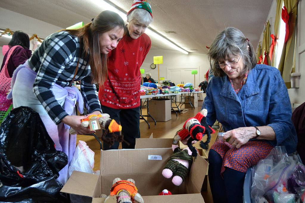 Farah Durham collects two homemade dolls for her two daughters from Cindy Mckay as Mary Taylor watches. (Matthew Nash/Olympic Peninsula News Group)