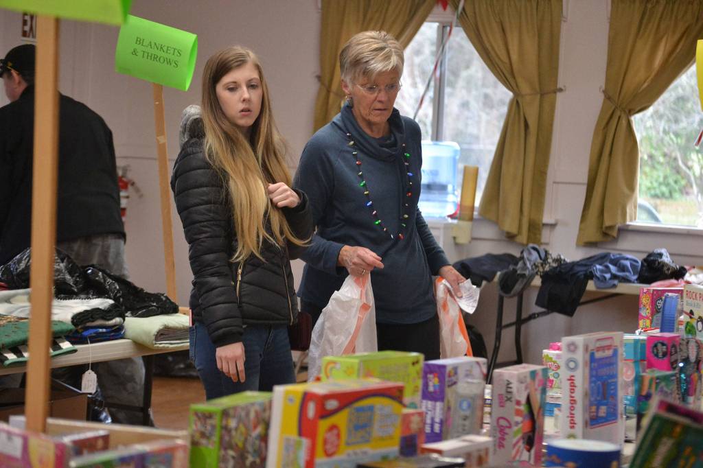 Haley Mack looks for presents for her two children ages 2 and 12 with Cindy Titterness, a volunteer with Sequim Community Aid. Mack said she was looking for fun stuff to do together. (Matthew Nash/Olympic Peninsula News Group)