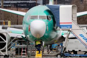 A worker looks up underneath a Boeing 737 MAX jet Monday, Dec. 16, 2019, in Renton, Wash. Shares of Boeing fell before the opening bell on a report that the company may cut production of its troubled 737 MAX or even end production all together. (AP Photo/Elaine Thompson)