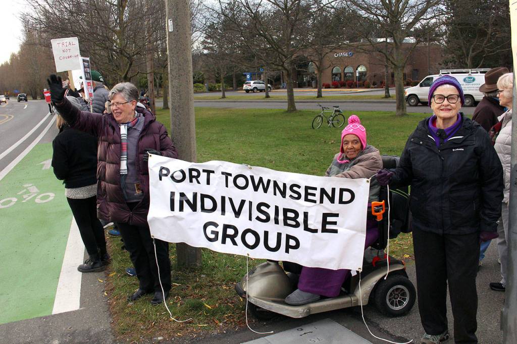 Paula McDonnel, left, and Marcia Hartshorn hold the sign for the Port Townsend Indivisible Group on Tuesday afternoon at the rally.