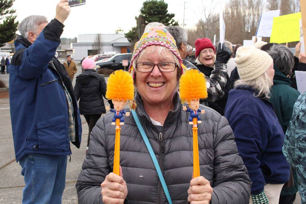 Kristina Wilkening holds two toilet bowl brushes with caricatures of President Donald Trump during the impeachment support rally Tuesday afternoon.
