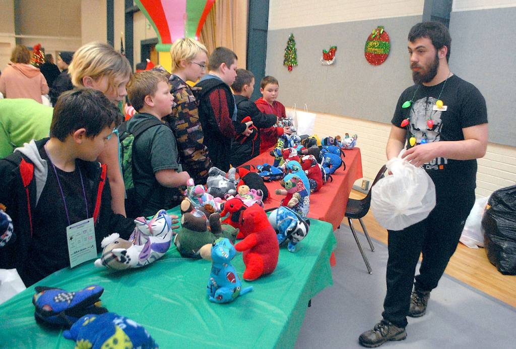 Volunteer Jakobee Ellis, right, stocks a table of stuffed animals created by prisoners at the Clallam Bay Corrections Center to be given away to children as Christmas presents. (Keith Thorpe/Peninsula Daily News)