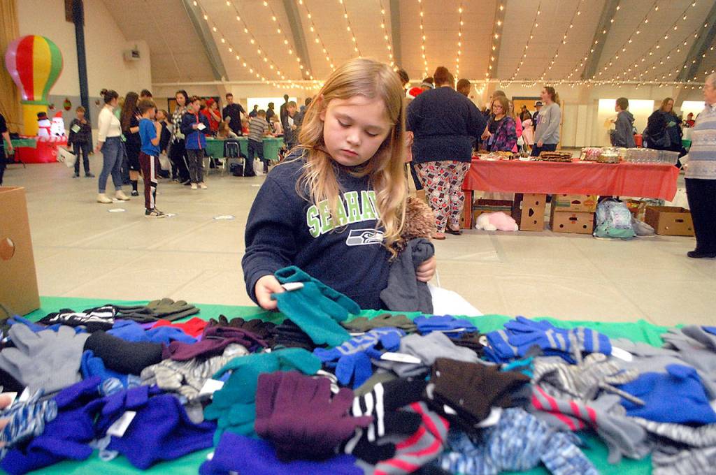 Jayden DeGoede, 8, makes her selection from a table filled with gloves and mittens during the Boys & Girls Club Christmas party at Vern Burton Community Center in Port Angeles. (Keith Thorpe/Peninsula Daily News)