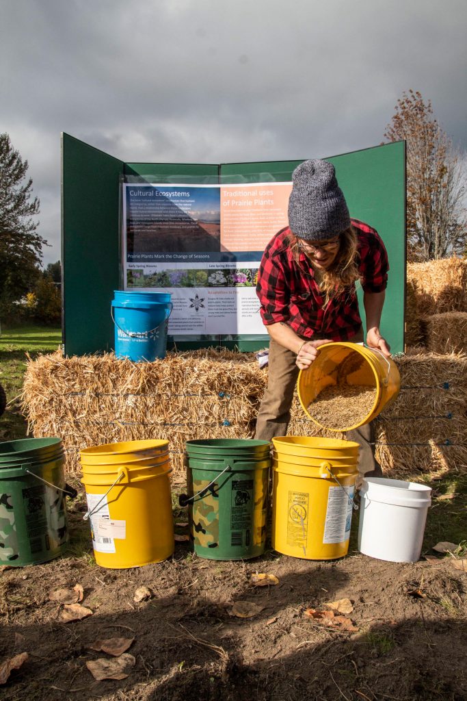 Traditional Foods Project assistant Mackenzie Grinnell sorts wildflower seeds into buckets for planting. (Tiffany Royal)