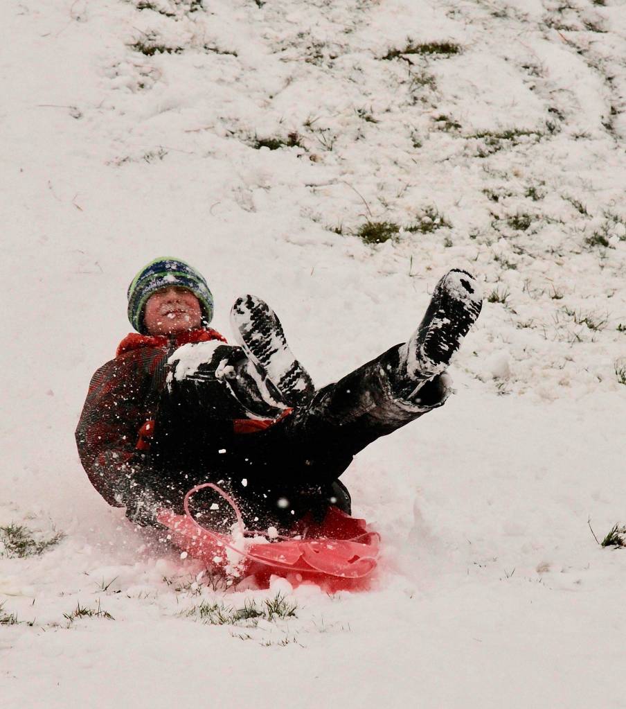 Matthew Miller, 12, slides down the hill on the Stevens Middle School campus Monday morning after the Port Angeles School District canceled school due to the snowfall. (Dave Logan/for Peninsula Daily News)