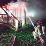 Firefighters battle a fire at a Chimacum home Monday night as smoke pours from its eaves. (East Jefferson Fire-Rescue)