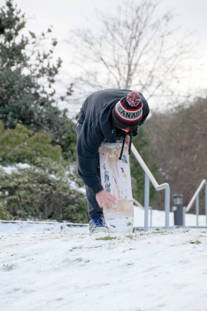 Lucas Chase, 14, adds more wax to the underside of his makeshift snowboard.