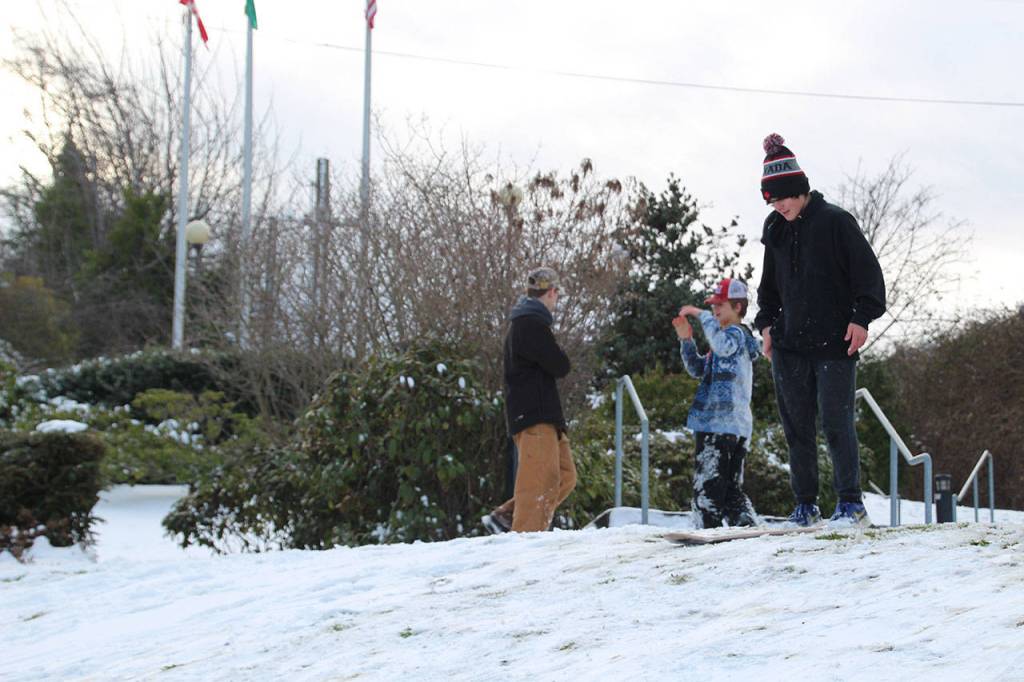 Lucas Chase, 14, gets ready to ride his makeshift snowboard with his friends Jack Harrelson, 15, and Blake McGowan, 15, behind him. (Maureen Heaster/Peninsula Daily News)