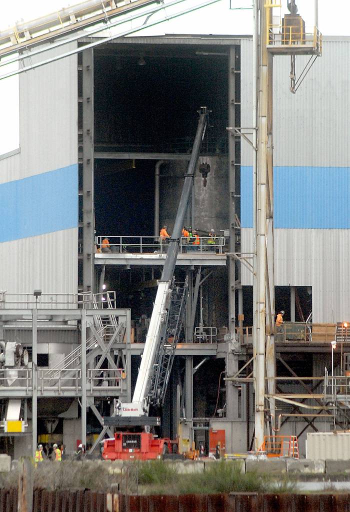 A crane pokes through an opening in the side of a building at the McKinley Paper Company mill in Port Angeles on Tuesday, Jan. 21, 2020, as the mill undergoes retooling to begin cardboard production. (Keith Thorpe/Peninsula Daily News)