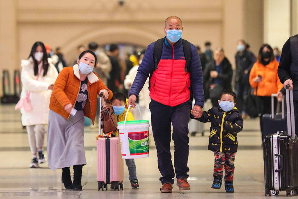 In this photo taken Tuesday, Jan. 21, 2020, travelers wearing face masks walk with their luggage at Hankou Railway Station in Wuhan in southern Chinas Hubei province. The U.S. on Tuesday reported its first case of a new and potentially deadly virus circulating in China, saying a Washington state resident who returned last week from the outbreaks epicenter was hospitalized near Seattle. (Chinatopix via AP)