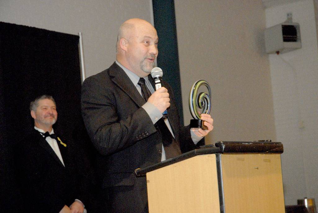 Ken Simpson of Angeles Electric holds up his Business of the Year Award as emcee Tim Tucker looks on. (Keith Thorpe/Peninsula Daily News)